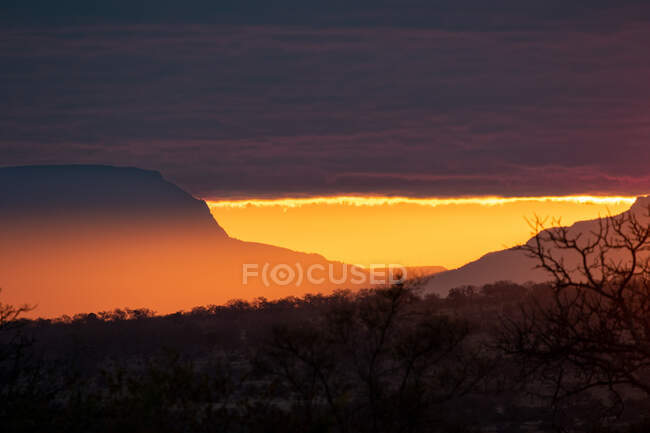 L'horizon au coucher du soleil, de grandes montagnes révèlent une lumière dorée — Photo de stock