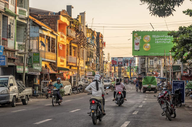 Mawlamyine, devantures et circulation sur la route au coucher du soleil, motos et piétons. — Photo de stock