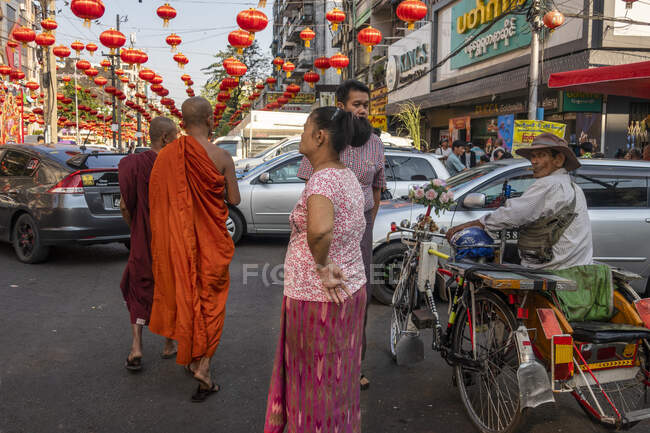 Buddhist monks on busy street in downtown Yangon decorated with red chinese lanterns in preparation for Chinese New Year celebrations Myanmar — Stock Photo