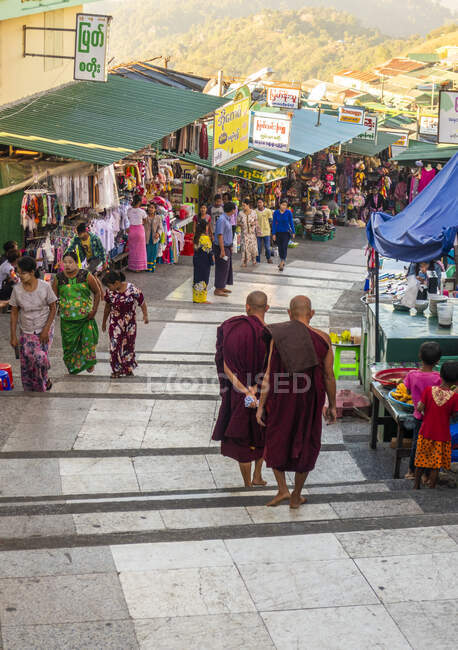 Moines descendant la colline Kyaiktiyo, marches et passerelle, étals de marché et les gens. — Photo de stock