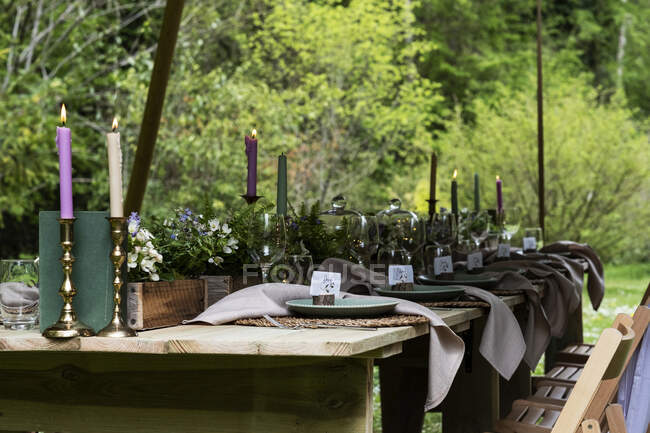 Mesa de jantar com velas e configurações de lugar rústico para uma cerimônia de nomeação da floresta. — Fotografia de Stock