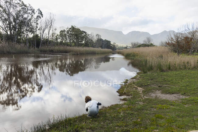 Молодий хлопчик грає на березі річки, пласка спокійна вода і відкриті простори — стокове фото