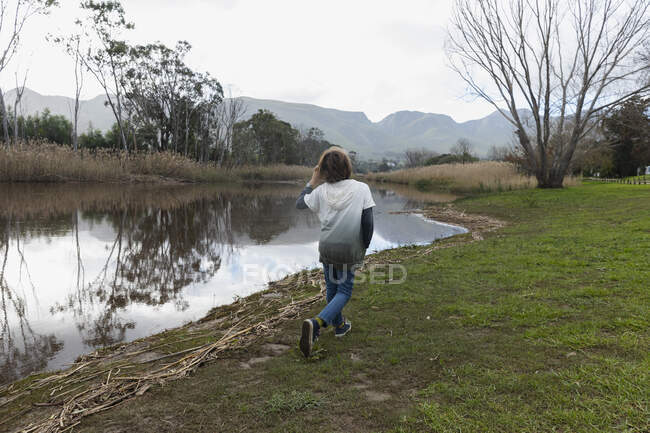 Jovem brincando em uma margem do rio, água calma plana e espaços abertos — Fotografia de Stock
