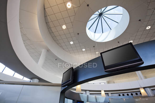 A view from below to a round dome ceiling with a central skylight. Display screens. — Stock Photo