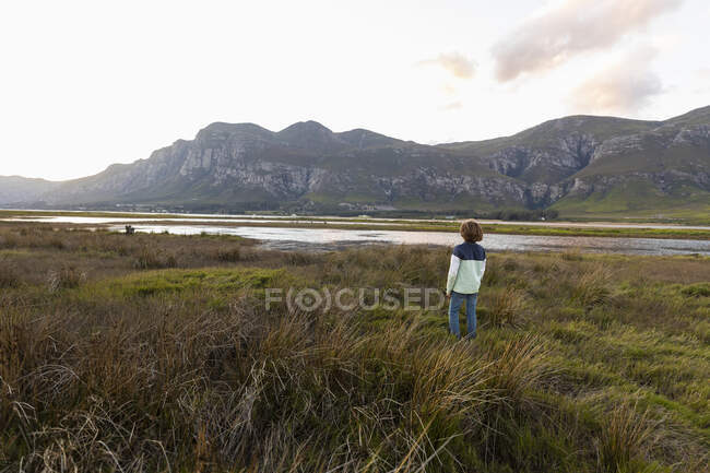 A boy exploring the shore of a lagoon in the shadow of the Kleinriver mountain range — Stock Photo