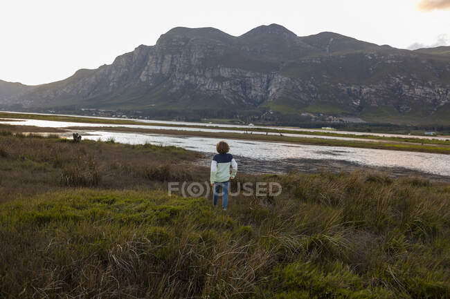 Ragazzo che esplora la riva di una laguna all'ombra delle montagne — Foto stock