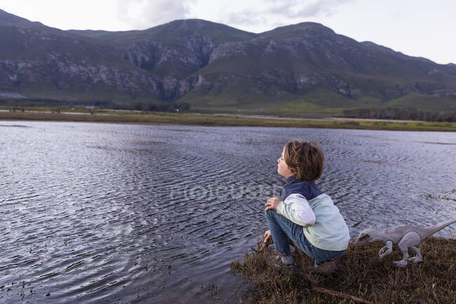 Хлопчик, що досліджує берег лагуни в тіні гірського хребта Кляйнрівер. — стокове фото
