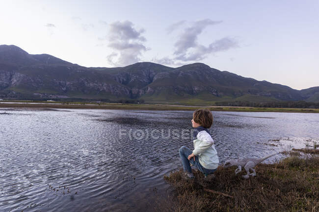 Um menino explorando a costa de uma lagoa na sombra da cordilheira Kleinriver — Fotografia de Stock