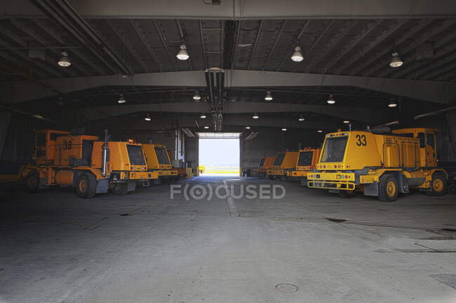 Snow ploughs and maintenance vehicles in a garage at an airport. — Stock Photo