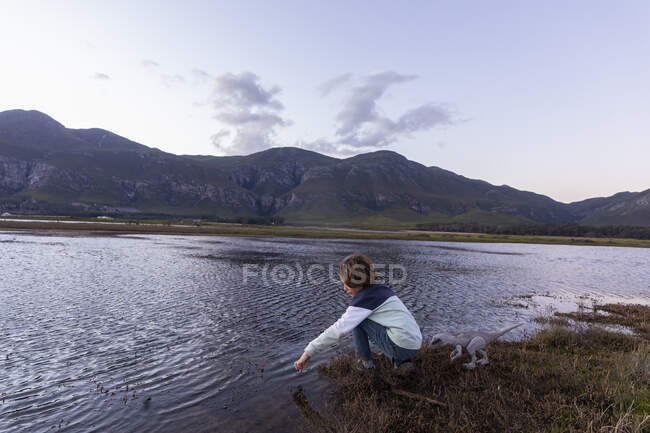 Ein Junge erkundet das Ufer einer Lagune im Schatten der Gebirgskette des Kleinriver — Stockfoto