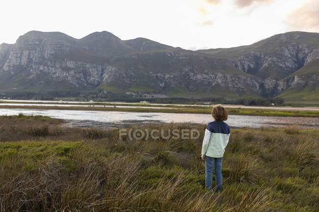 Un ragazzo che esplora la riva di una laguna all'ombra della catena montuosa del Kleinriver — Foto stock