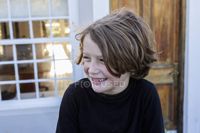 Молодий хлопчик сміється, дивиться вбік, голова і плечі — стокове фото