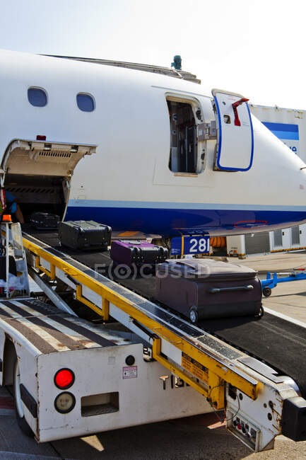 A passenger aircraft on the ground, baggage on a moving belt being loaded — Stock Photo
