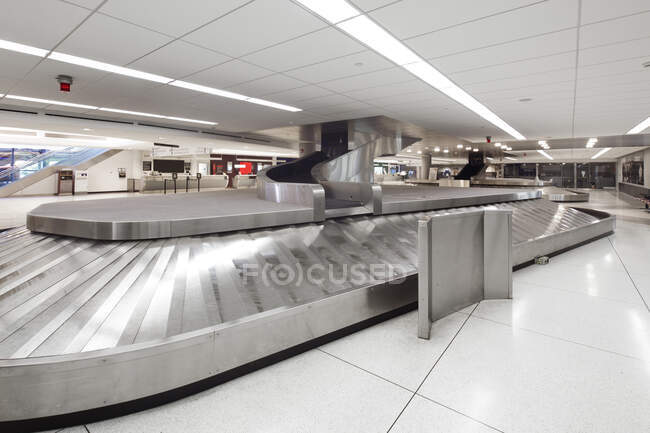 Área de reclamo de equipaje del aeropuerto vacía, carruseles y pantallas de información. - foto de stock