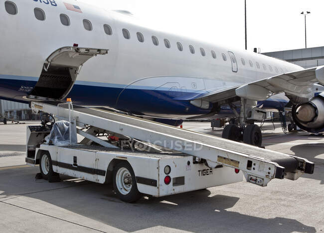 Um avião de passageiros em um jetway com um veículo de caminhão de bagagem. — Fotografia de Stock