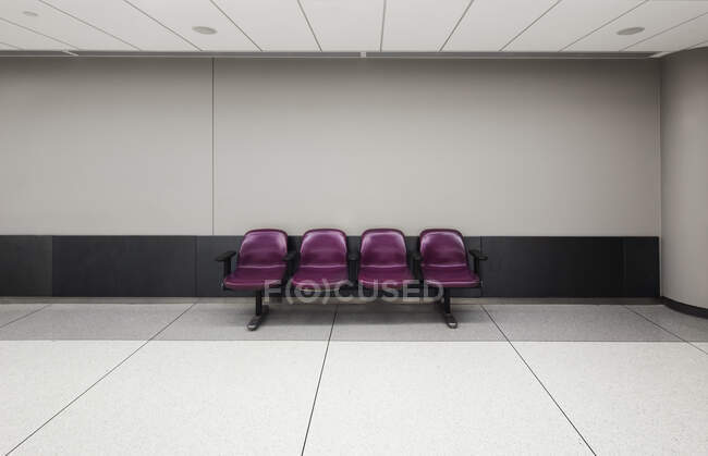 Una fila de cuatro asientos fijos en un aeropuerto vacío - foto de stock