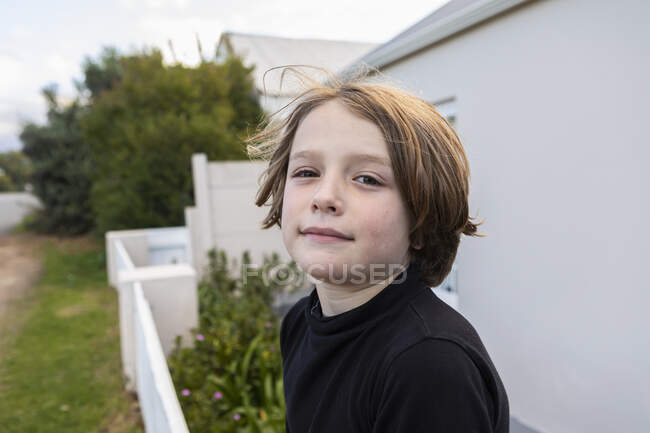 Garçon de huit ans avec une expression sérieuse en dehors de sa maison — Photo de stock