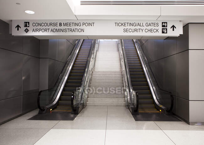 Um par de escadas rolantes e sinais de informação — Fotografia de Stock