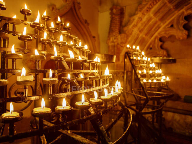 Kerzen in Gestellen einer historischen Kirche anzünden — Stockfoto