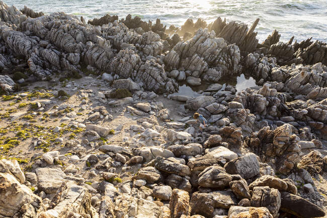 Rapaz explorando as rochas irregulares e piscinas de rocha na costa do Oceano Atlântico — Fotografia de Stock