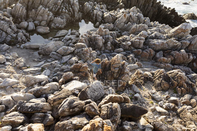 Ragazzo che esplora le rocce frastagliate e le piscine rocciose sulla costa atlantica, De Kelders, Western Cape, Sud Africa. — Foto stock