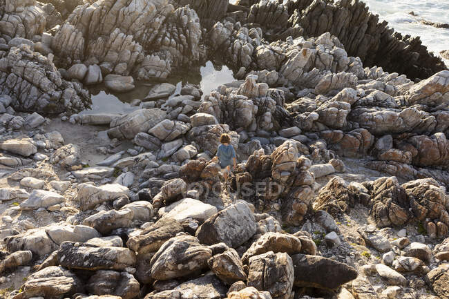 Junge erkundet die zerklüfteten Felsen und Felspfützen an der Atlantikküste, De Kelders, Western Cape, Südafrika. — Stockfoto
