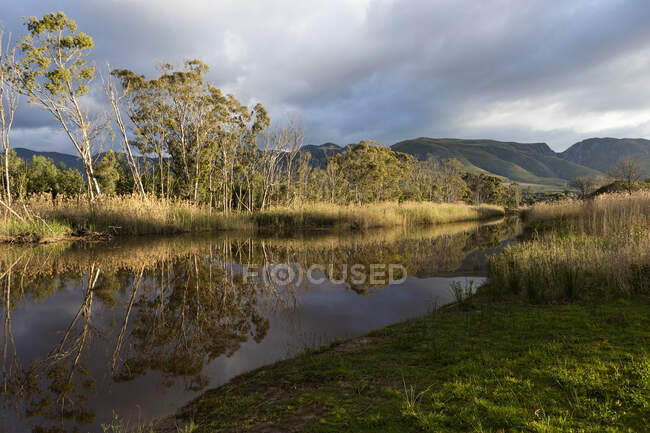 Clouds gathering above the Klein River, mountain range and flat calm water. — Stock Photo