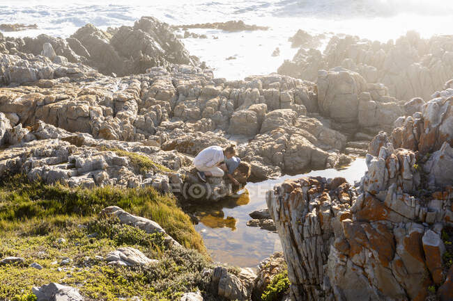 Deux enfants explorent les rochers déchiquetés et les piscines rocheuses sur la côte de l'océan Atlantique, De Kelders, Western Cape, Afrique du Sud. — Photo de stock