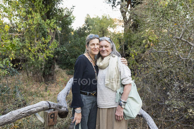 Adult woman and her mother on a walkway through the trees at a safari camp, Botswana. — Stock Photo