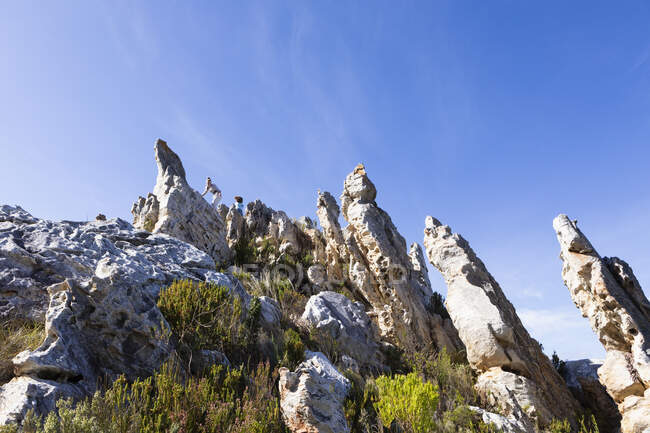 Deux enfants grimpent au sommet de grandes formations rocheuses de grès sur un sentier naturel. — Photo de stock