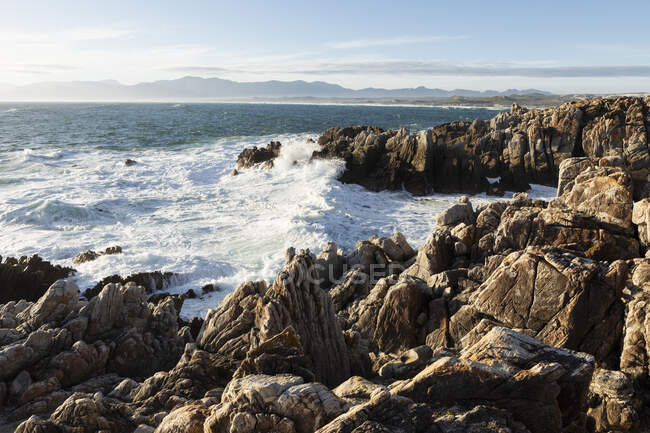 Les rochers déchiquetés et les piscines rocheuses sur un littoral océanique avec des vagues se brisant — Photo de stock