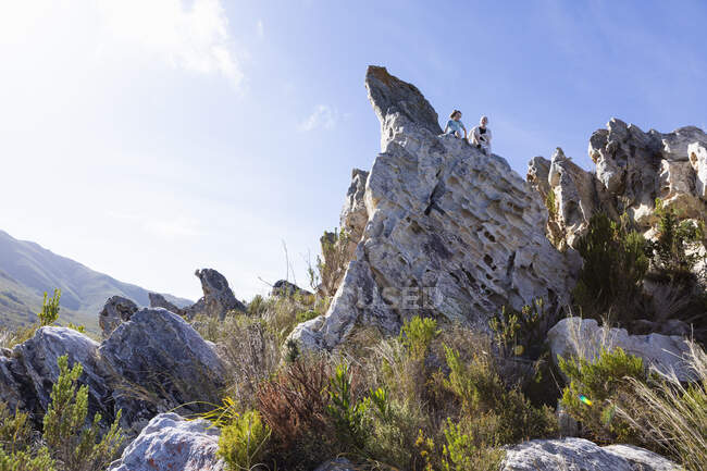 Duas crianças escalando em cima de grandes formações rochosas de arenito em uma trilha da natureza. — Fotografia de Stock