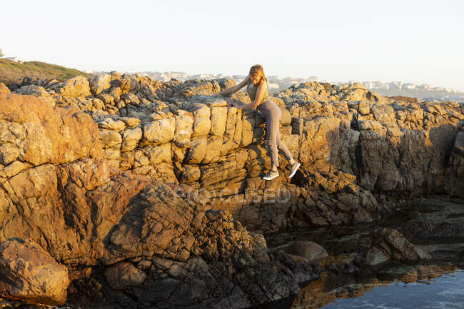 Adolescente che esplora le rocce frastagliate sulla costa De Kelders sul Capo Occidentale. — Foto stock