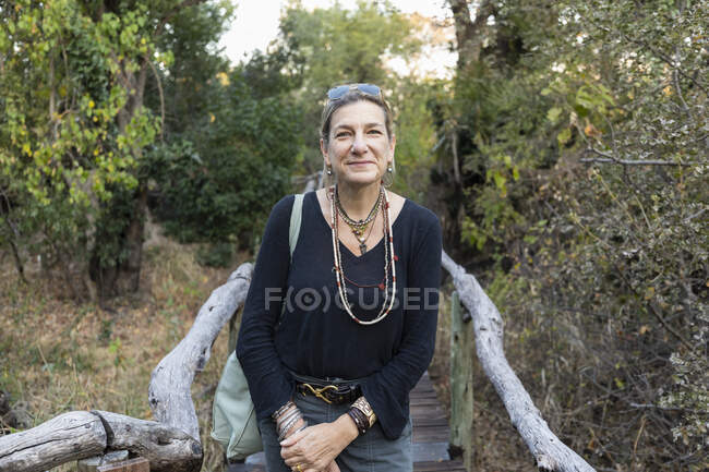 Adult woman on a walkway through trees at a camp in the Okavango Delta, Botswana. — Stock Photo