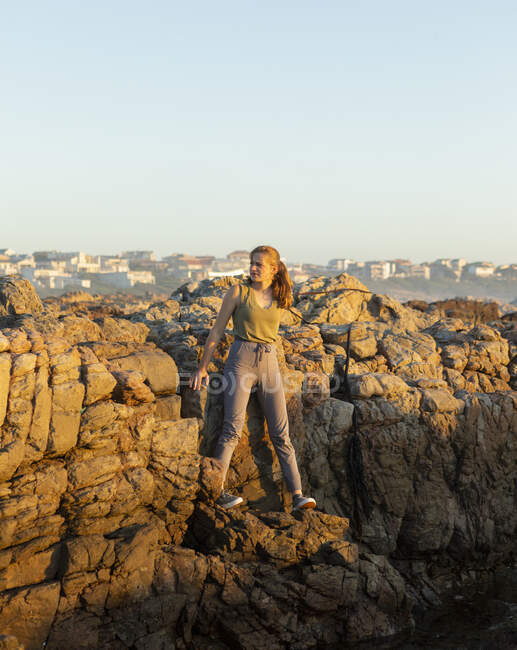 Ragazza adolescente in piedi sulle rocce frastagliate della costa De Kelders sul Capo Occidentale. — Foto stock