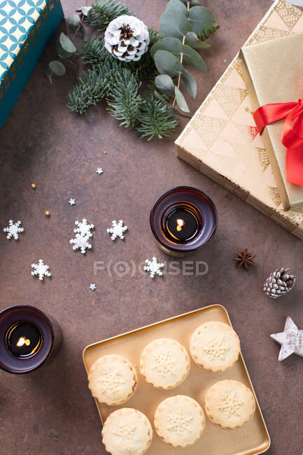 Christmas, overhead view of mince pies on a plate and star shapes and lit candles. — Stock Photo