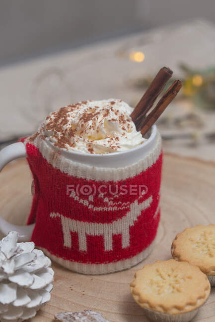 Christmas, a mug of hot chocolate or eggnog with a knitted wraparound cozy and mince pies. — Stock Photo