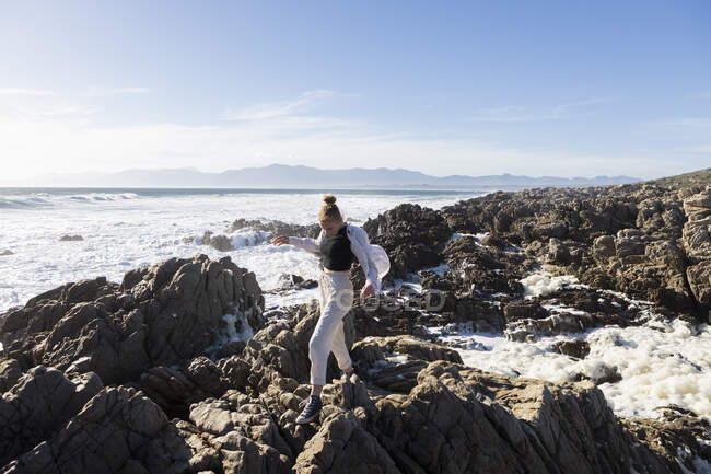 Девочка-подросток, исследующая зазубренные скалы и бассейны на побережье Атлантического океана, Де Келдерс, Западный Кейп, Южная Африка. — стоковое фото
