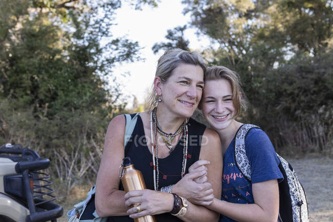 Madre e figlia adolescente nel cespuglio in safari, fianco a fianco sorridente, Botswana. — Foto stock