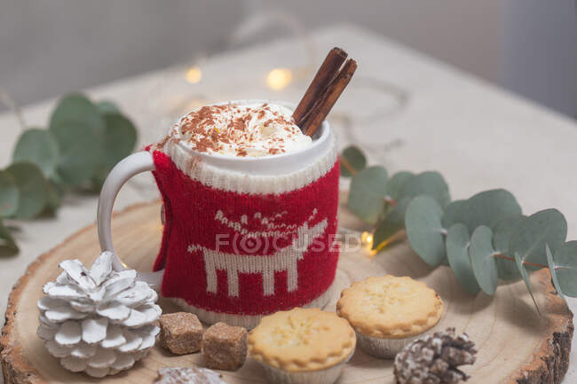 Christmas, a mug of hot chocolate or eggnog with a knitted wraparound cosy and mince pies. — Stock Photo