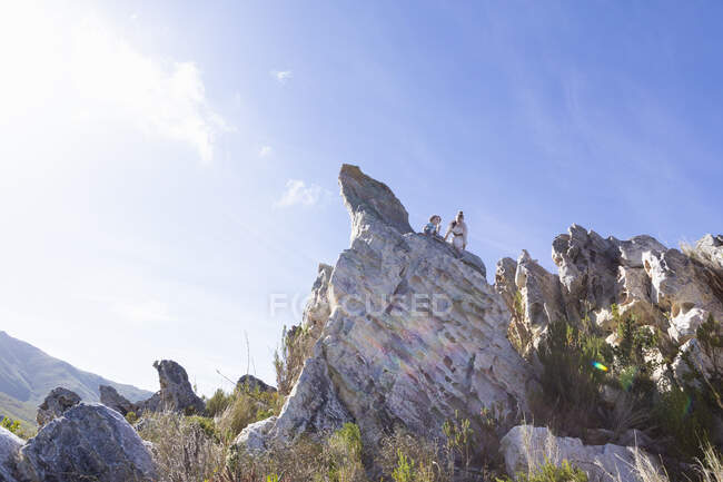 Dos niños escalando sobre grandes formaciones rocosas de arenisca en un sendero natural. - foto de stock