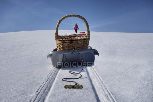 Sled transporting picnic basket over hilly snowy winter landscape — Stock Photo