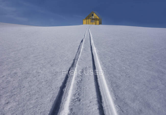 Sled tracks on hillside to yellow rural house in Estonia. — Stock Photo