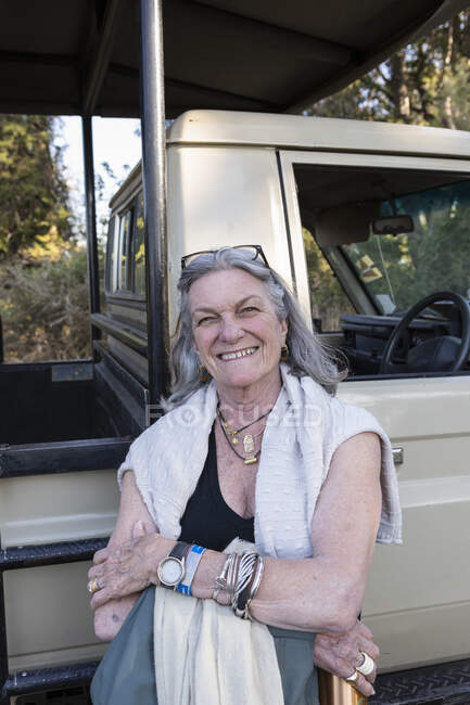 Donna anziana sorridente accanto a un veicolo safari in Botswana. — Foto stock
