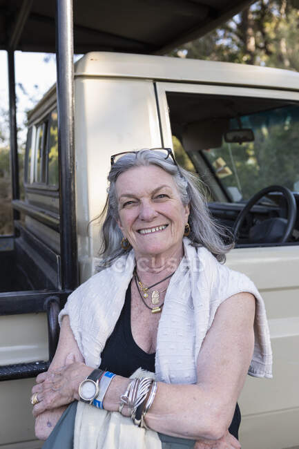 Senior woman smiling standing by a safari vehicle in Botswana. — Stock Photo