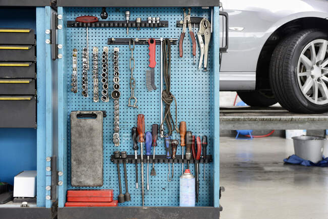 Outils sur un tableau bleu dans une armoire de rangement organisée en rangées dans un atelier de réparation automobile. — Photo de stock