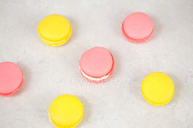 Розовые и желтые макароны, вкусное сладкое печенье на столе. — стоковое фото