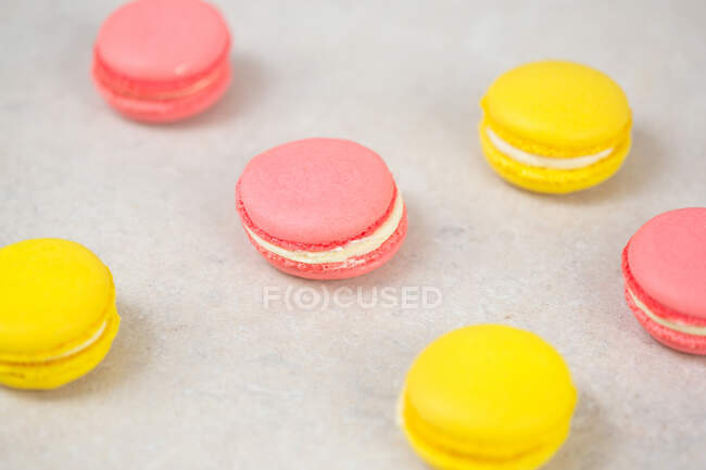 Рожеві та жовті макаруни, смачне солодке печиво на столі . — стокове фото