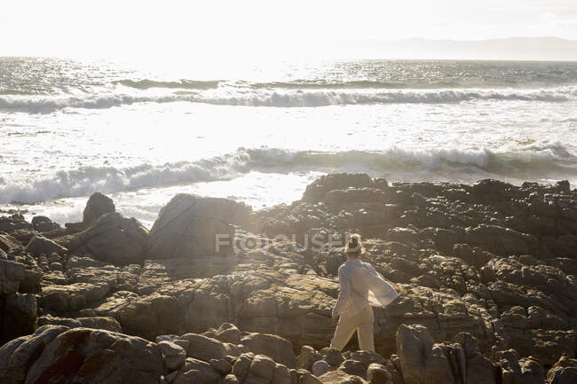 Adolescente explorando as rochas irregulares e piscinas de rocha na costa do Oceano Atlântico, De Kelders, Western Cape, África do Sul. — Fotografia de Stock