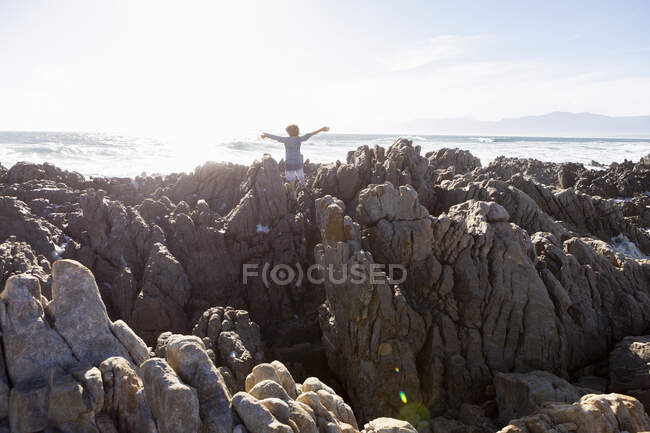 Ragazzo che esplora le rocce frastagliate e le piscine rocciose sulla costa atlantica, De Kelders, Western Cape, Sud Africa. — Foto stock